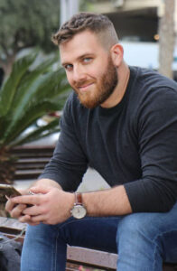 לקוח מזוקן יושב על ספסל עם הטלפון